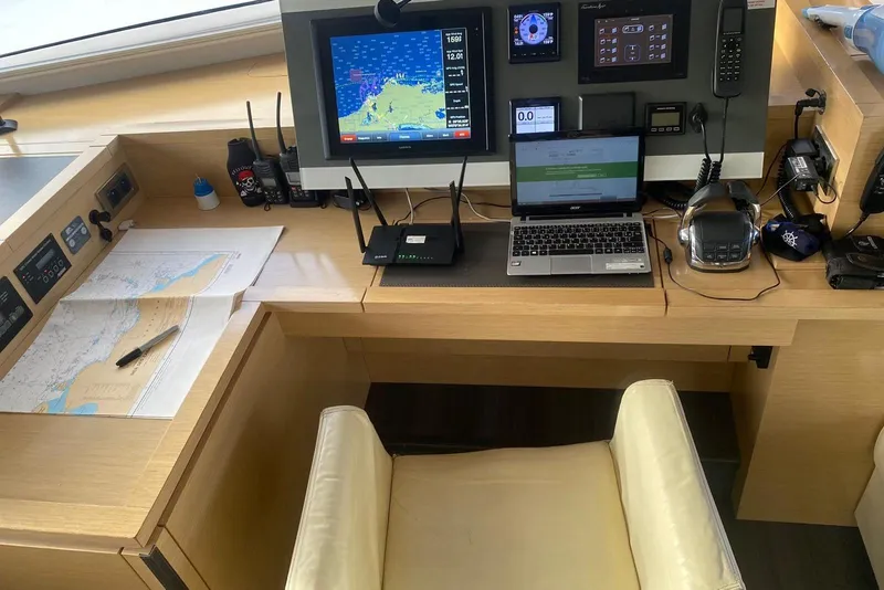 Slide: The Image of Navigation station on 2014 FONTAINE PAJOT 63 yacht with maps, laptop, and communication devices. - 49