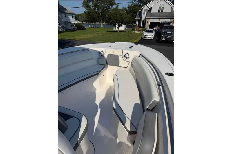 Slide: The Image of 2019 Tidewater 232 CC Adventure boat interior with seating and speakers, parked near waterfront homes. - 5