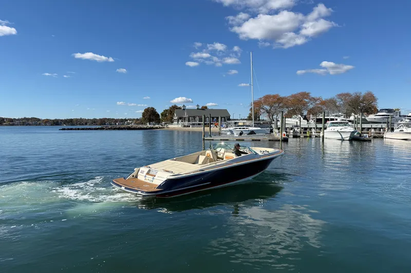 Slide: The Image of 2018 Chris-Craft Launch 30 boat cruising in a marina under a clear blue sky. - 2