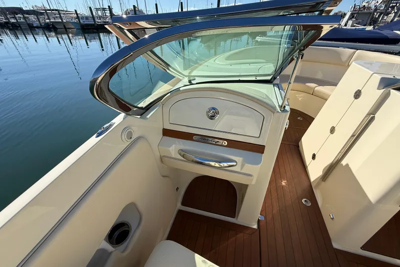 Slide: The Image of 2018 Chris-Craft Launch 30 interior with elegant wood and leather detailing at a marina. - 26