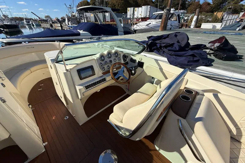 Slide: The Image of 2018 Chris-Craft Launch 30 boat interior with beige seating and wooden dashboard at a marina. - 27