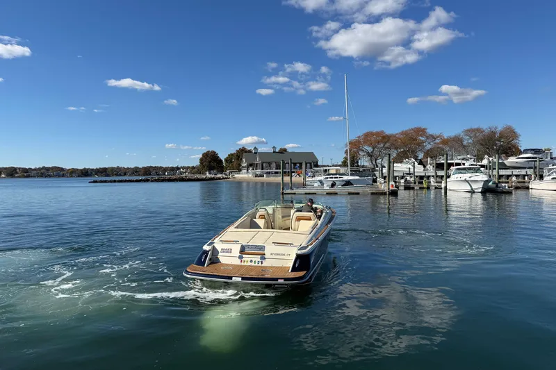 Slide: The Image of 2018 Chris-Craft Launch 30 boat cruising in a scenic marina under a clear blue sky. - 3