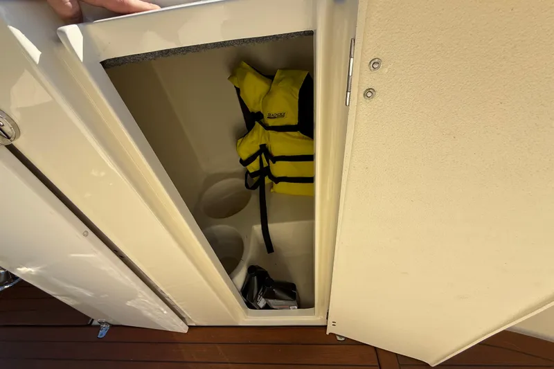 Slide: The Image of Storage compartment on 2018 Chris-Craft Launch 30 with life jacket and cup holders. - 39