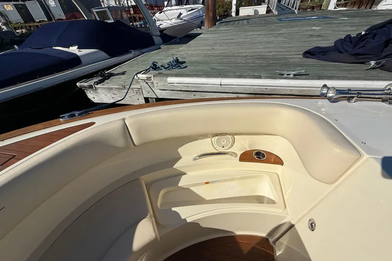 Slide: The Image of 2018 Chris-Craft Launch 30 boat interior with beige seating and wooden accents at a dock. - 45