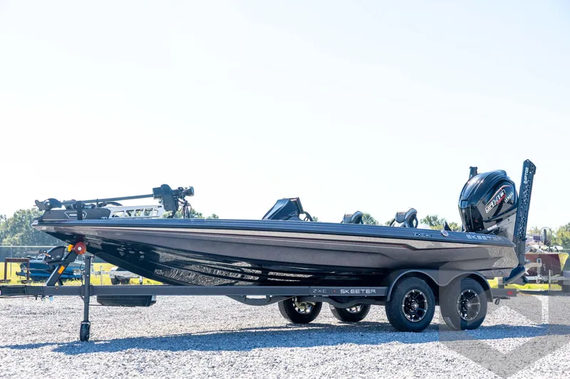 The Image of 2026 Skeeter ZXE20 boat on trailer, side view, outdoors on gravel. - 1