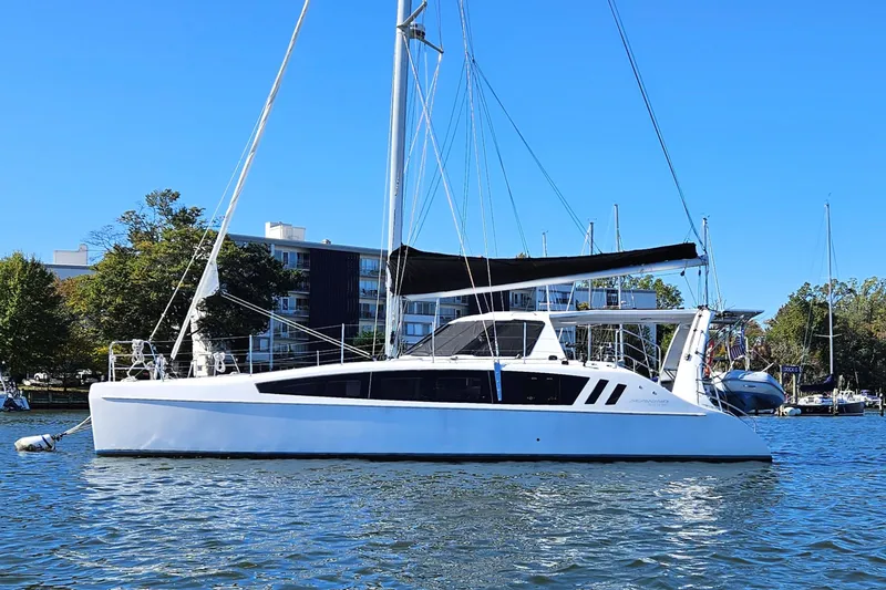 The Image of 2022 Seawind 1160 Lite catamaran sailing on calm waters near a marina. - 1