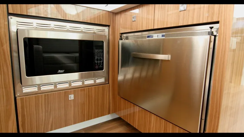 Slide: The Image of Modern kitchen appliances in 2024 Cruisers Yachts 50 Cantius, featuring a microwave and stainless steel fridge. - 30