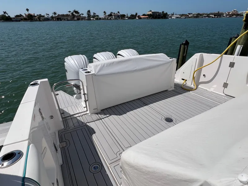 Slide: The Image of 2022 Regal 38 SAV boat deck with seating, overlooking calm waters and distant shoreline. - 11