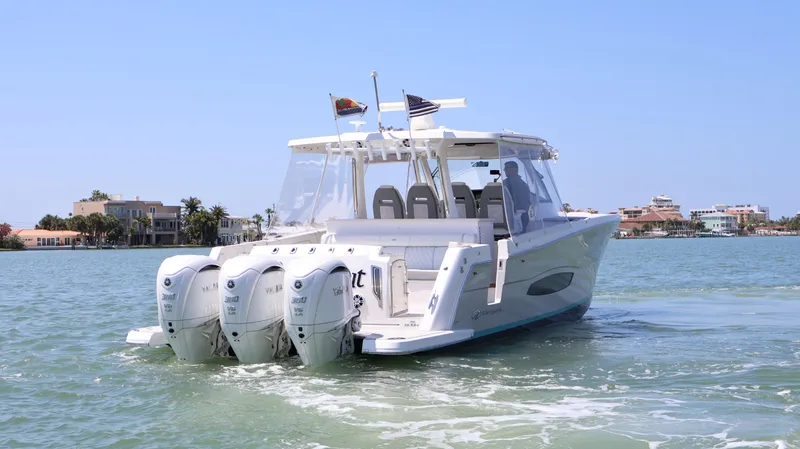 Slide: The Image of 2022 Regal 38 SAV boat cruising on a sunny day with triple outboard engines. - 7