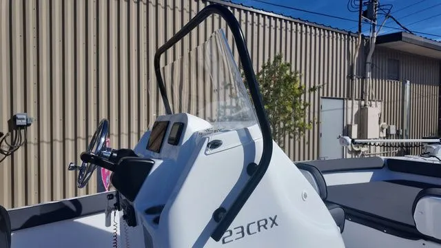Slide: The Image of 2026 ALK2 Powerboats 23CRX console with steering wheel and windshield, docked outdoors. - 32