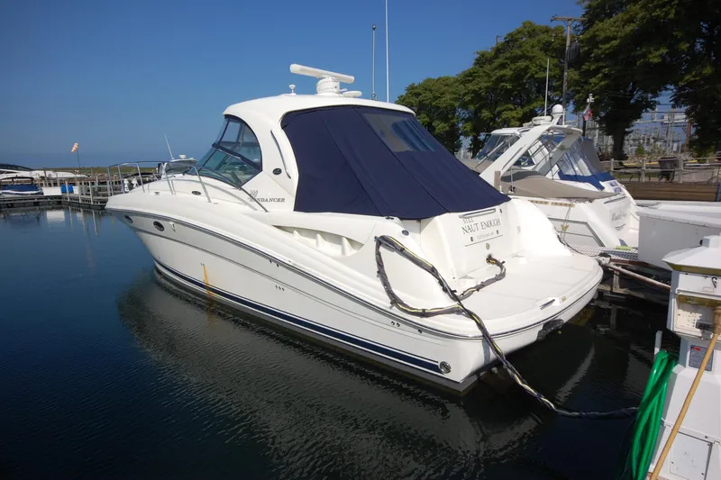 The Image of 2004 Sea Ray 390 Sundancer yacht docked in a marina, featuring sleek design and blue cover. - 0