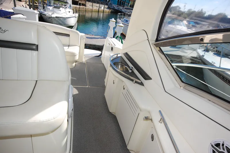 Slide: The Image of 2004 Sea Ray 390 Sundancer yacht interior with white seating and kitchenette, docked at marina. - 15
