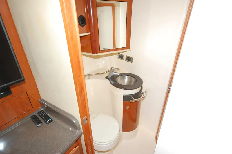 Slide: The Image of 2004 Sea Ray 390 Sundancer bathroom with sink, toilet, and wooden cabinetry. - 31