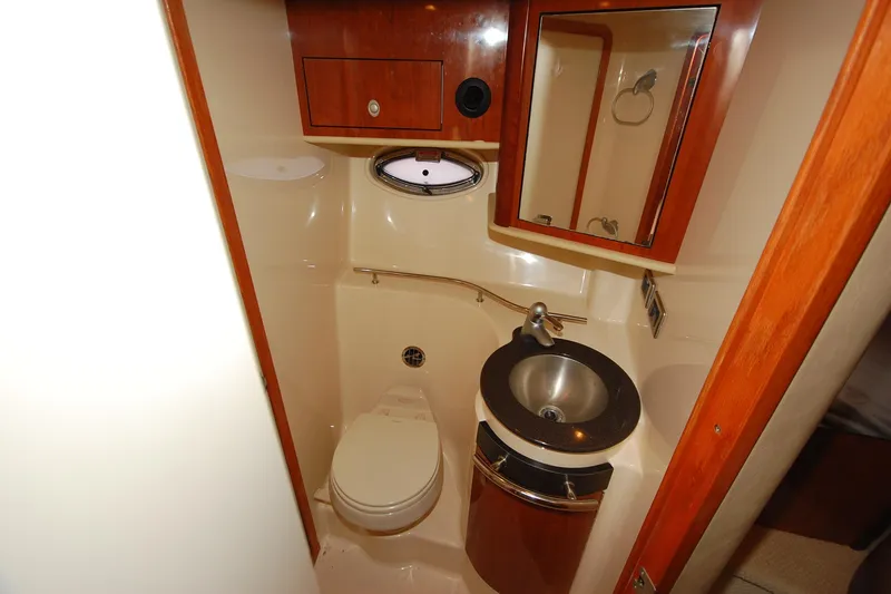 Slide: The Image of 2004 Sea Ray 390 Sundancer bathroom with sink, toilet, and wooden cabinetry. - 32