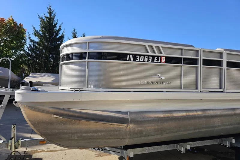 Slide: The Image of 2022 Bennington SX 21 Fishing pontoon boat on trailer, sunny day, trees in background. - 20