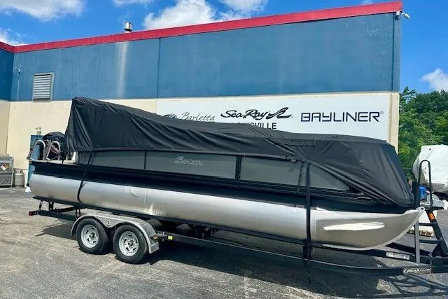 Slide: The Image of 2026 Barletta A22QC pontoon boat on trailer, covered, outside dealership. - 2