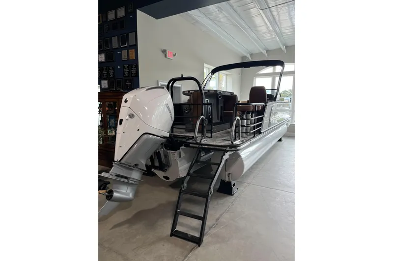 Slide: The Image of 2026 Starcraft RX 25 DL DC pontoon boat with outboard motor and ladder in showroom. - 7