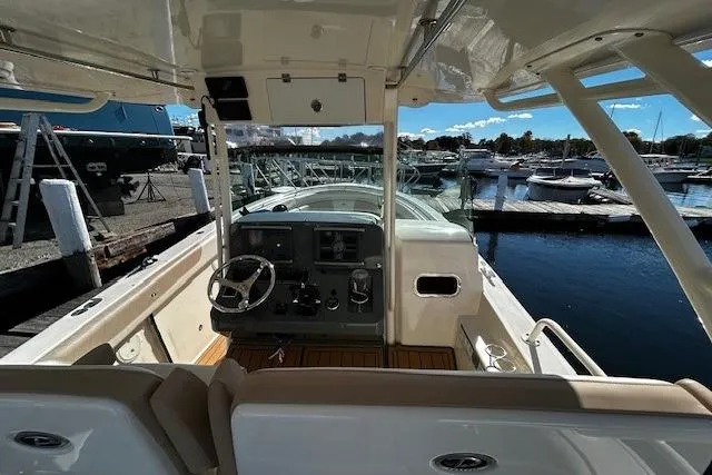 Slide: The Image of 2014 Pursuit ST 310 Sport boat interior at marina, featuring helm and seating. - 10