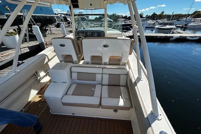 Slide: The Image of 2014 Pursuit ST 310 Sport boat interior with beige seating at a marina. - 11
