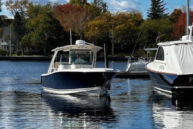 Slide: The Image of 2014 Pursuit ST 310 Sport boat on calm water, surrounded by autumn trees. - 2