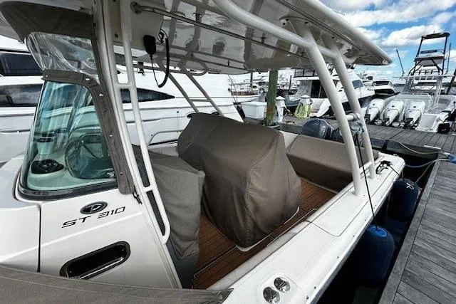 Slide: The Image of 2014 Pursuit ST 310 Sport boat docked, featuring covered seating and sleek design. - 5