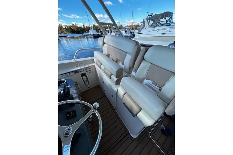 Slide: The Image of 2014 Pursuit ST 310 Sport boat interior with beige seating and steering wheel, docked at marina. - 8