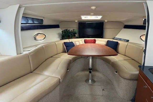 Slide: The Image of Interior of a 2006 Bayliner 325 yacht with beige seating and a wooden table. - 11