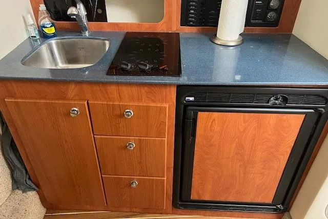 Slide: The Image of 2006 Bayliner 325 boat kitchenette with sink, stove, and mini fridge. - 12