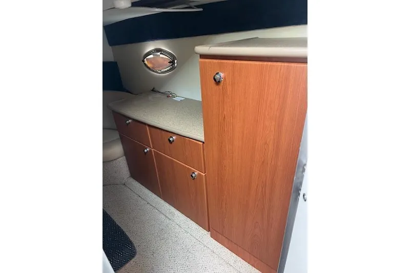 Slide: The Image of 2006 Bayliner 325 interior with wooden cabinets and porthole window. - 14