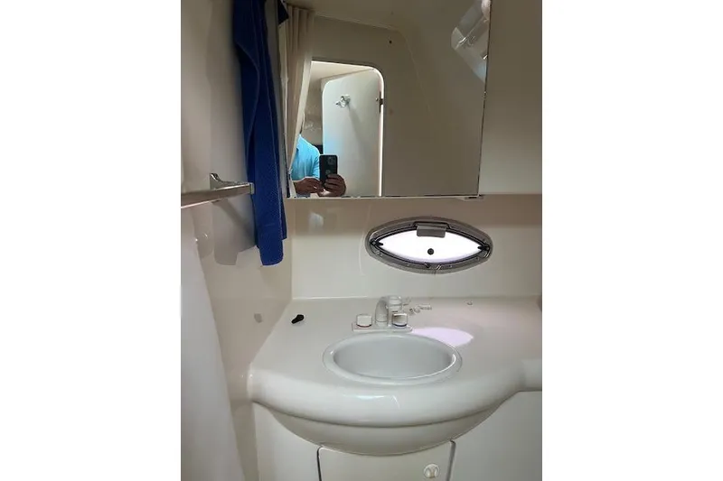 Slide: The Image of 2006 Bayliner 325 boat bathroom with sink, mirror, and porthole window. - 16