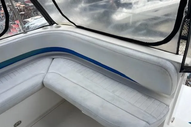 Slide: The Image of 2006 Bayliner 325 boat interior seating with blue accent and clear canopy. - 2