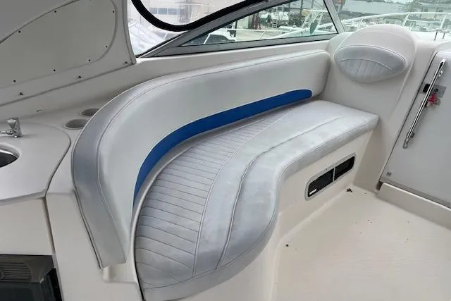Slide: The Image of 2006 Bayliner 325 boat interior with white and blue cushioned seating. - 5