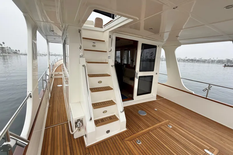Slide: The Image of 2009 Grand Banks 47 Heritage EU yacht with teak deck and staircase, docked by calm waters. - 61