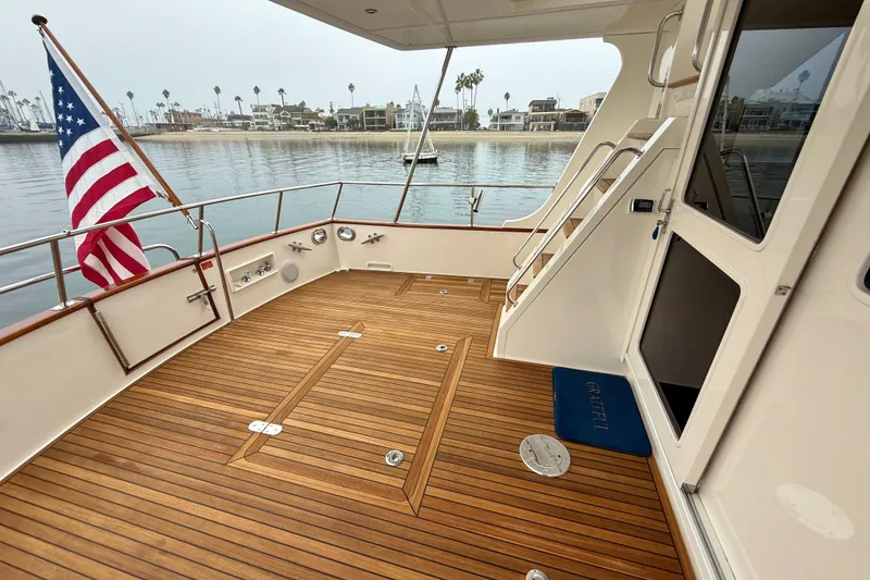 Slide: The Image of Grand Banks 47 Heritage EU 2009 yacht deck with American flag, docked by waterfront homes. - 63