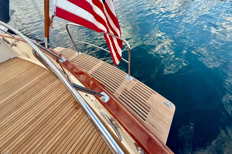 Slide: The Image of Teak deck of 2009 Grand Banks 47 Heritage EU yacht with American flag, overlooking water. - 99