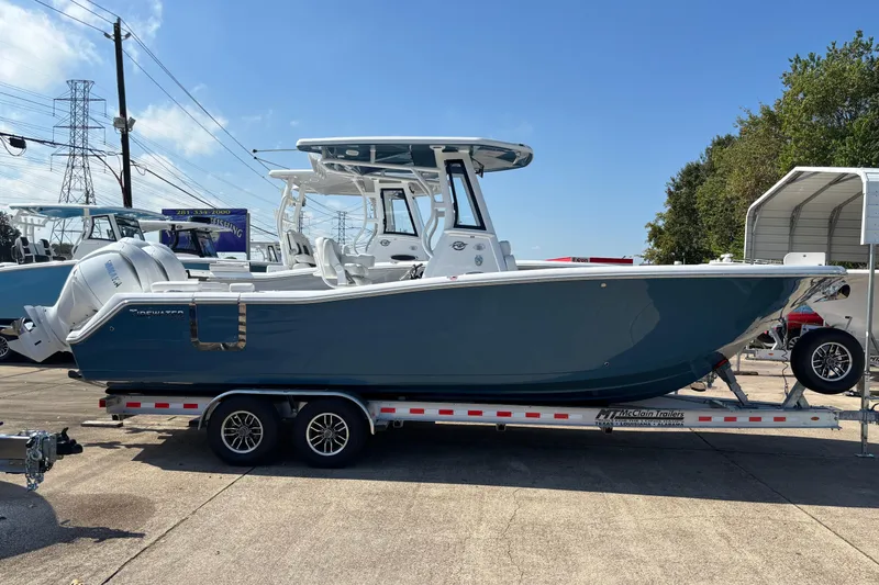 Slide: The Image of 2026 Tidewater 272 LXF boat on trailer, blue hull, dual engines, outdoor display. - 1
