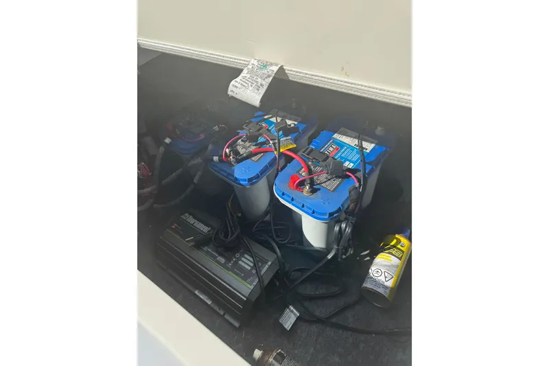 Slide: The Image of 2019 Yamaha Boats 242 Limited S battery compartment with connected cables and maintenance supplies. - 11