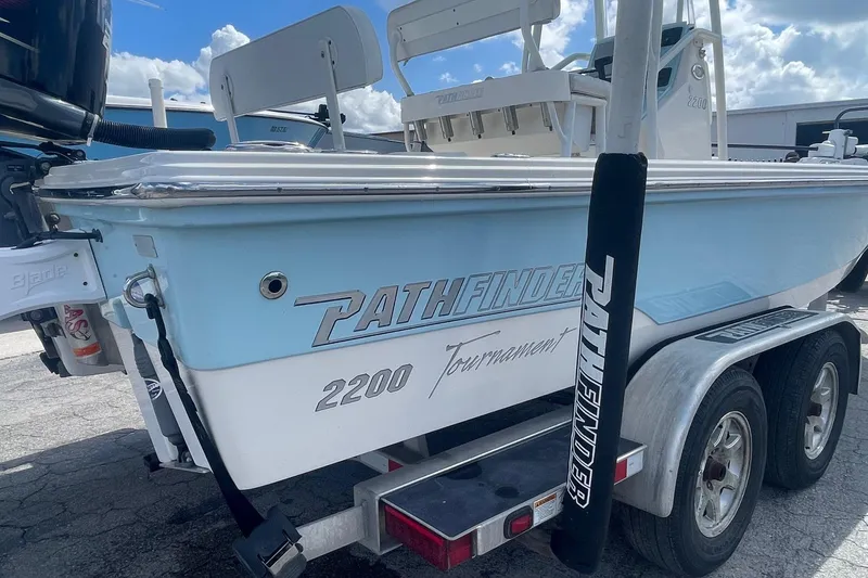 Slide: The Image of 2020 Pathfinder 2200 Tournament Edition boat on trailer, light blue hull, sunny day. - 13