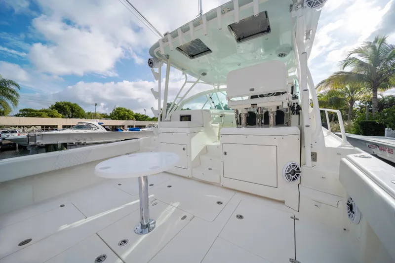 Slide: The Image of 2011 SeaVee 430 Sport Express boat interior with seating and table, under a clear sky. - 14