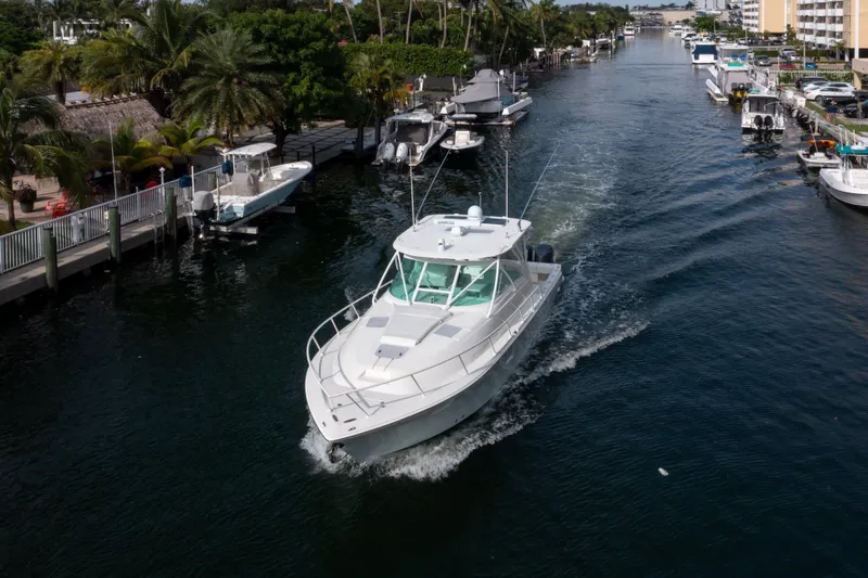 Slide: The Image of 2011 SeaVee 430 Sport Express cruising in a scenic canal with palm trees and boats. - 7