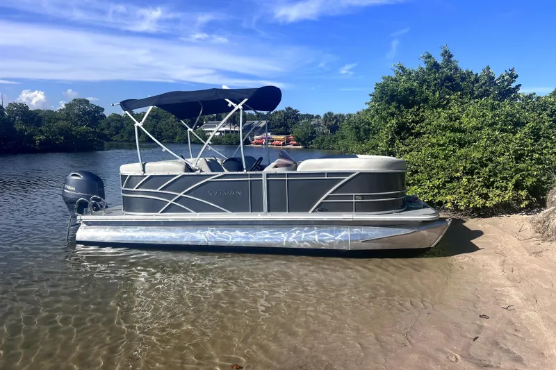 The Image of 2023 Sylvan Mirage 820 LZ pontoon boat docked on a sunny shoreline. - 0