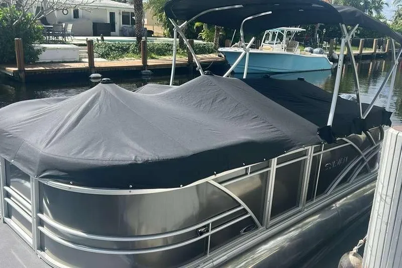 Slide: The Image of 2023 Sylvan Mirage 820 LZ pontoon boat with cover, docked by a canal. - 11