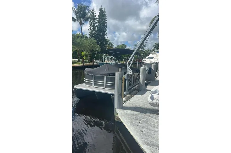 Slide: The Image of 2023 Sylvan Mirage 820 LZ pontoon boat docked by palm trees under cloudy sky. - 12