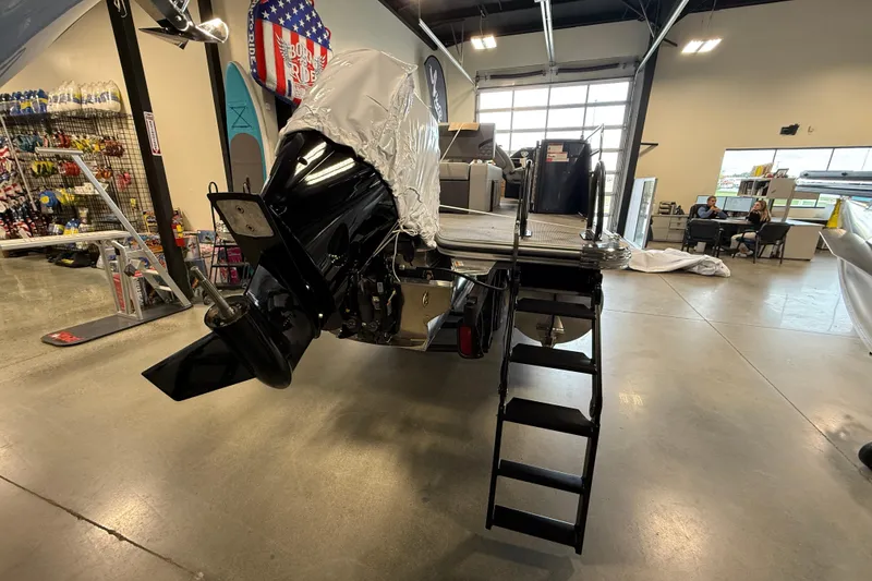 Slide: The Image of 2026 Crest Conquest 230 SLSC boat in showroom, rear view with motor and ladder. - 6