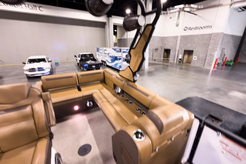 Slide: The Image of 2026 Montara Surf Boss EVO SL 23' boat interior with tan seating at an indoor exhibition. - 25