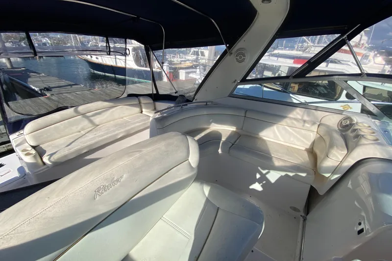 Slide: The Image of 2004 Rinker Fiesta Vee 342 boat interior with white seating and marina view. - 10
