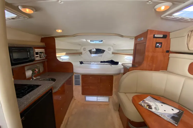 Slide: The Image of 2004 Rinker Fiesta Vee 342 interior with kitchenette, seating, and cozy cabin space. - 13