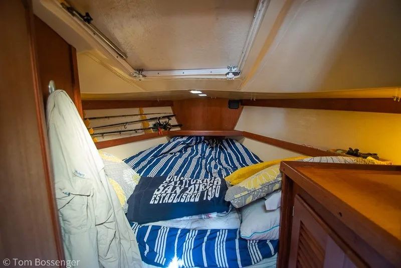 Slide: The Image of Cozy cabin interior of a 1985 Catalina 36 sailboat with striped bedding and fishing rods. - 20