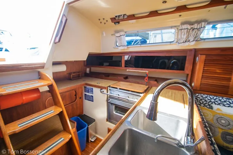 Slide: The Image of Interior of a 1985 Catalina 36 sailboat kitchen with sink, stove, and wooden cabinetry. - 7
