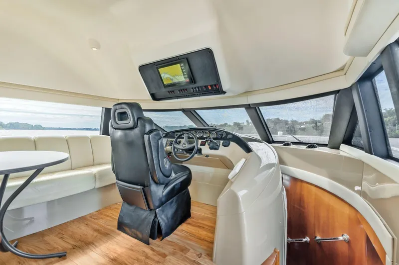Slide: The Image of Pilothouse interior of 2004 Carver 570 Voyager, featuring helm, seating, and panoramic windows. - 24